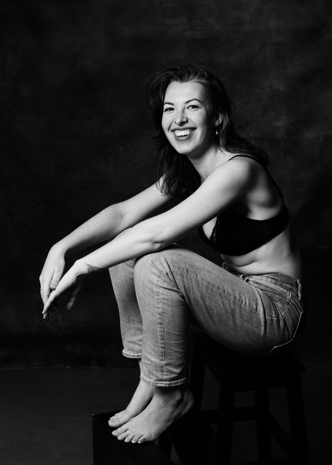 Woman in minimalist contemporary intimate portrait simple styling wearing jeans and a black bra.