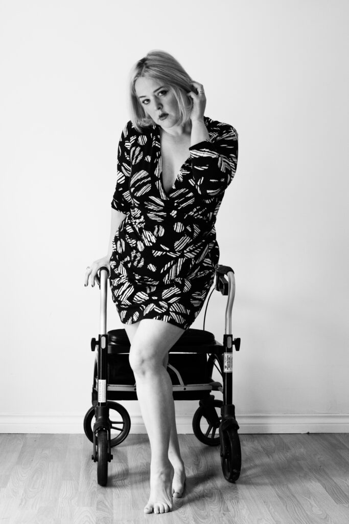 Woman wearing a dress standing in front of a walker with hand brushing thru her hair looking confident