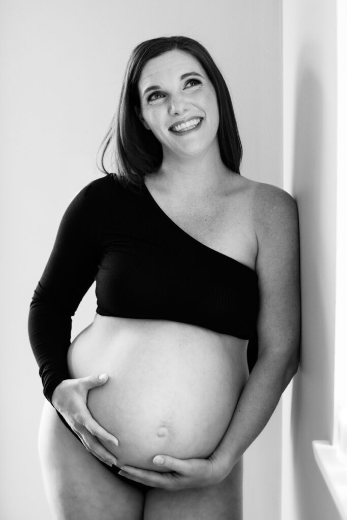 pregnant woman in black crop top and panties holding her bare belly