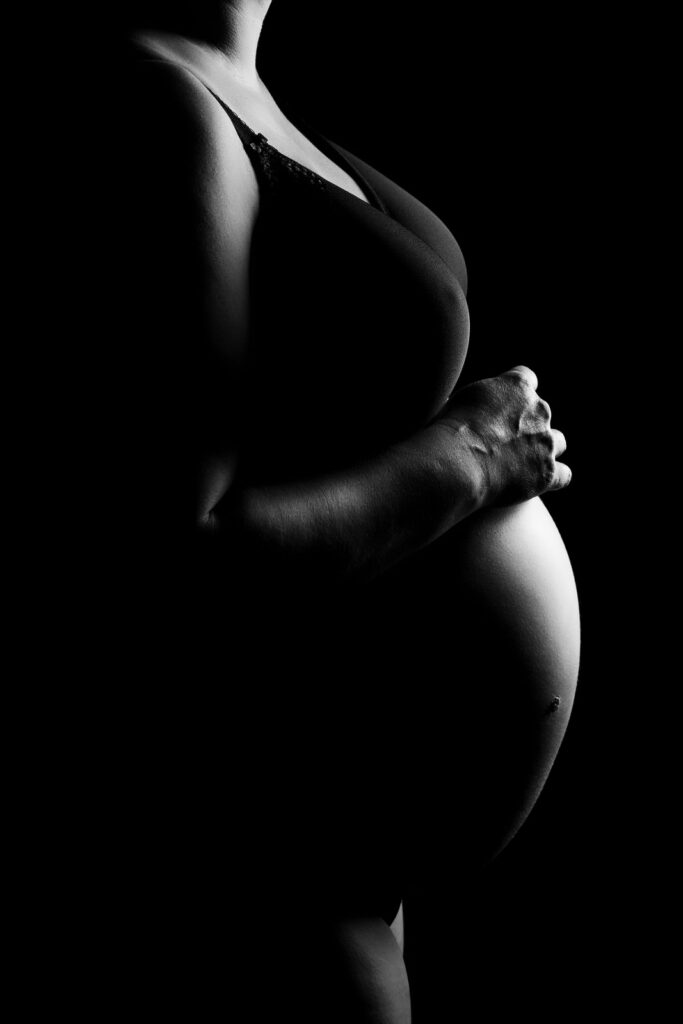 luxe maternity portrait in black and white of a woman's pregnant belly and one hand resting on her tummy