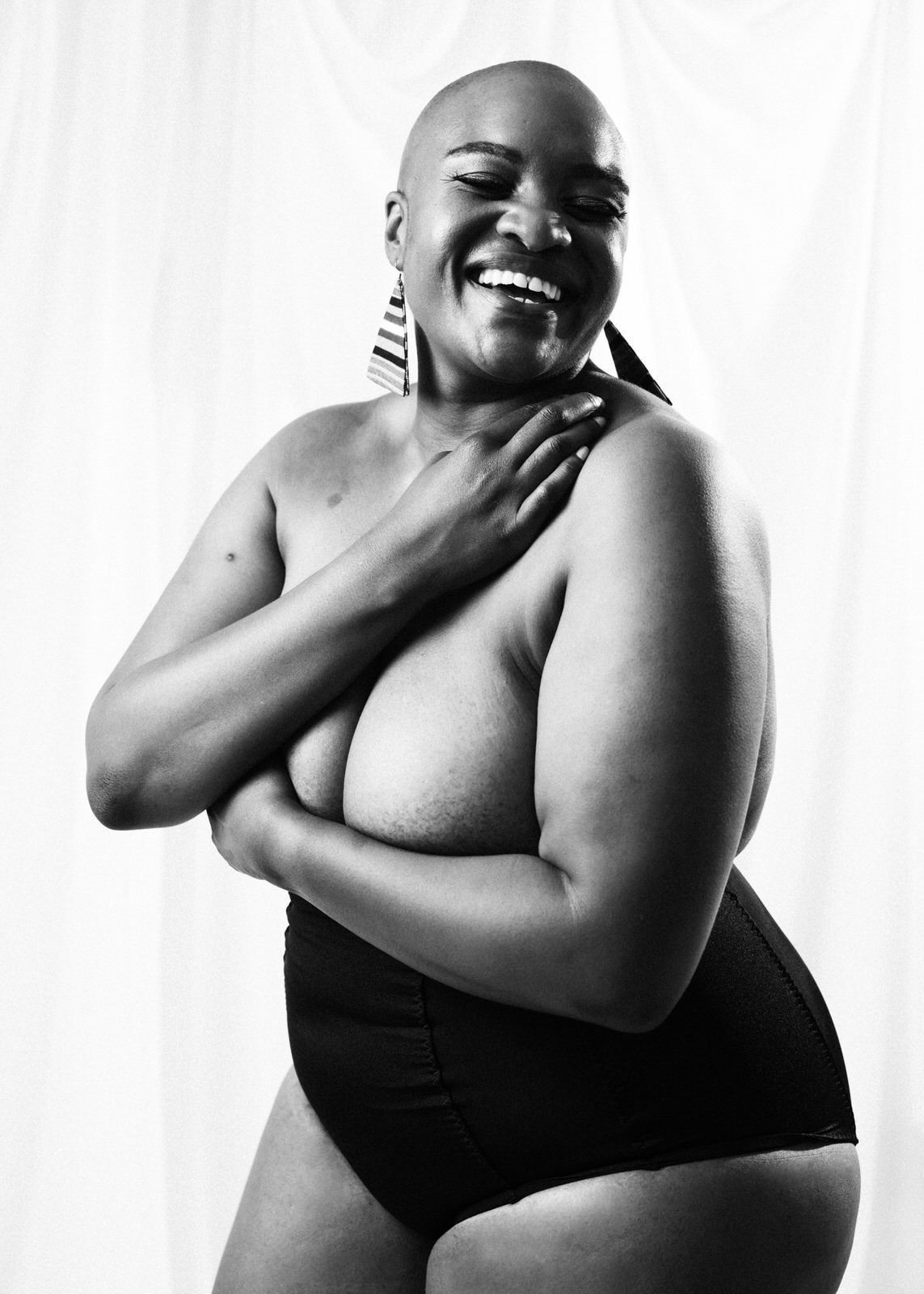 Black woman with alopecia in fine art nude portrait with arms crossed.
