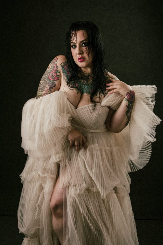 plus size boudoir photo woman in cream gown showing tattoos