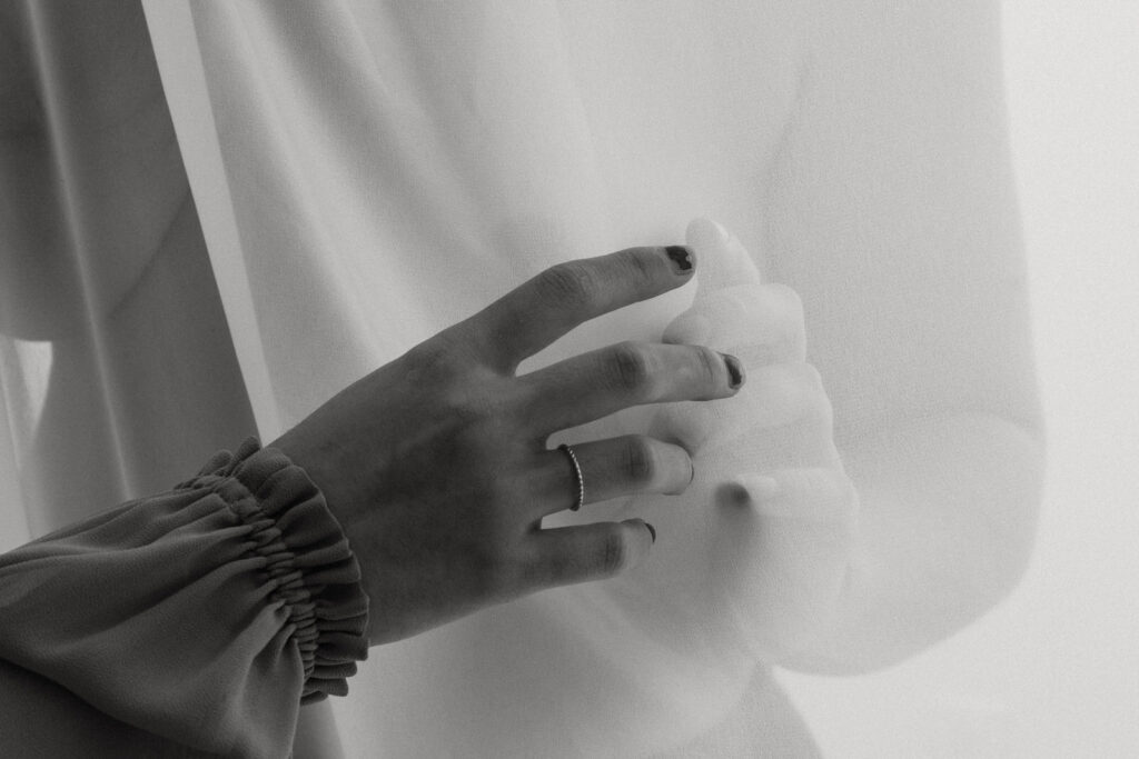 fine art nude photo a woman's hand in front of a white sheer sheet