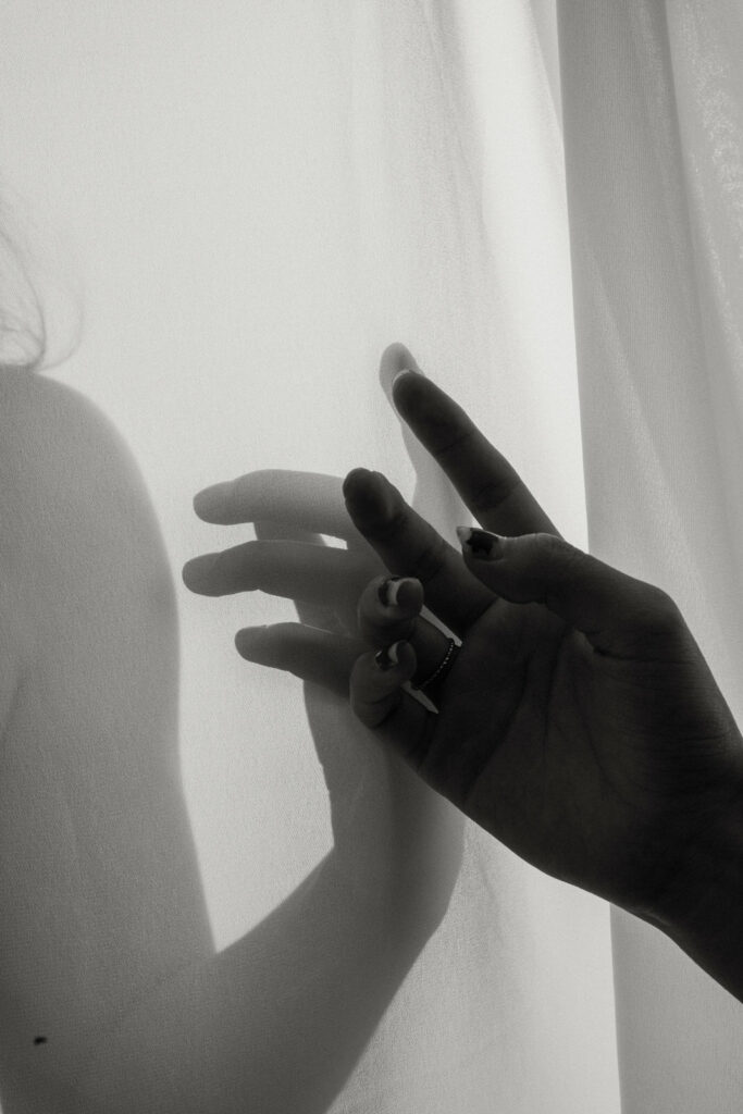 fine art nude of woman's hands making a shadow on sheer sheet