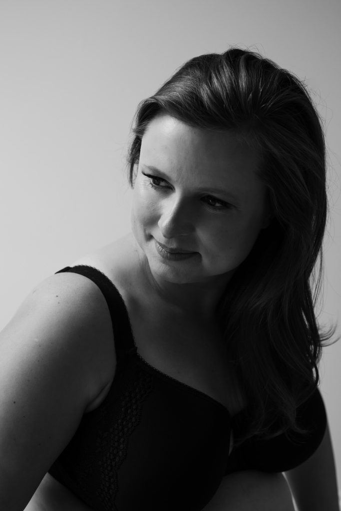 headshot of woman wearing bra looking over shoulder