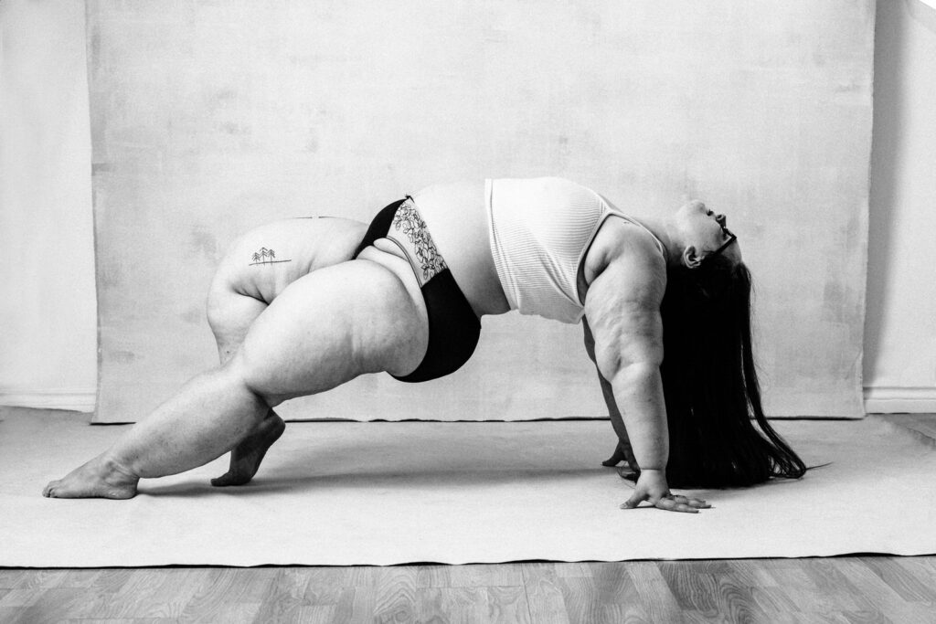 feminine embodiment boudoir image of woman wearing bralette and panties doing a bridge type pose with head and hair hanging down to floor