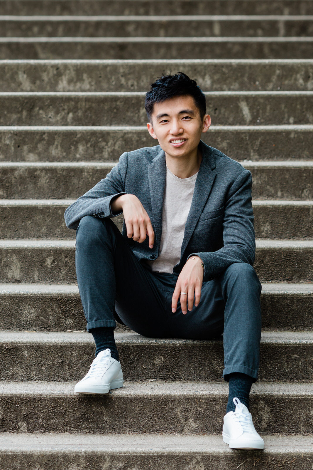 Professional male realtor in contemporary brand portrait wearing a suit sitting on stairs.