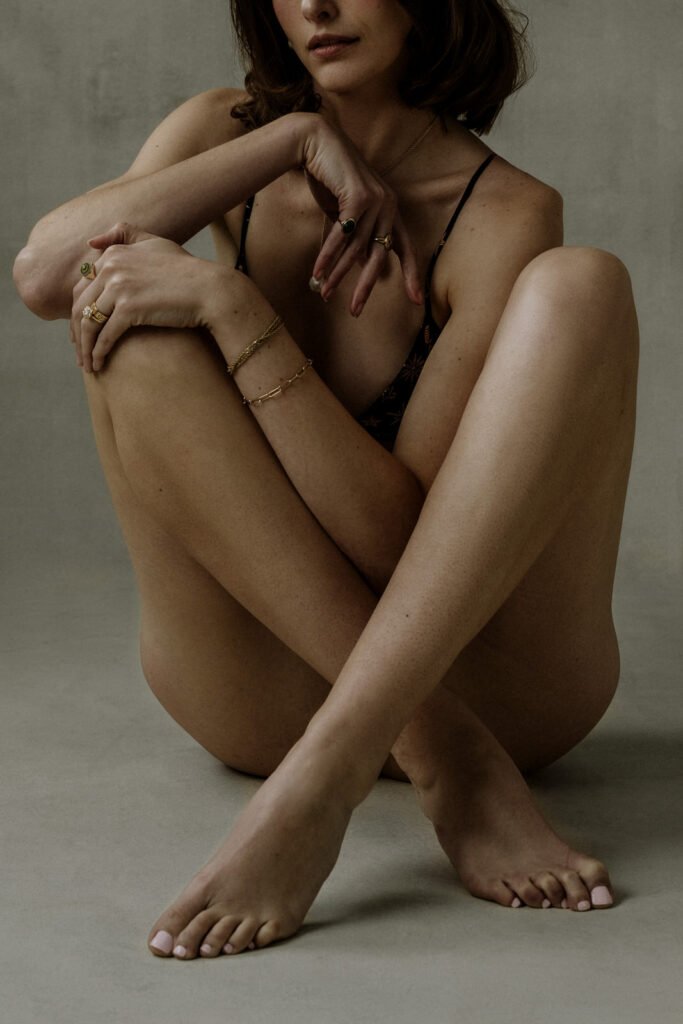 Vancouver Boudoir portrait of a brunette woman in an artistic effortless pose wearing gold jewelry posed on a hand painted canvas backdrop
