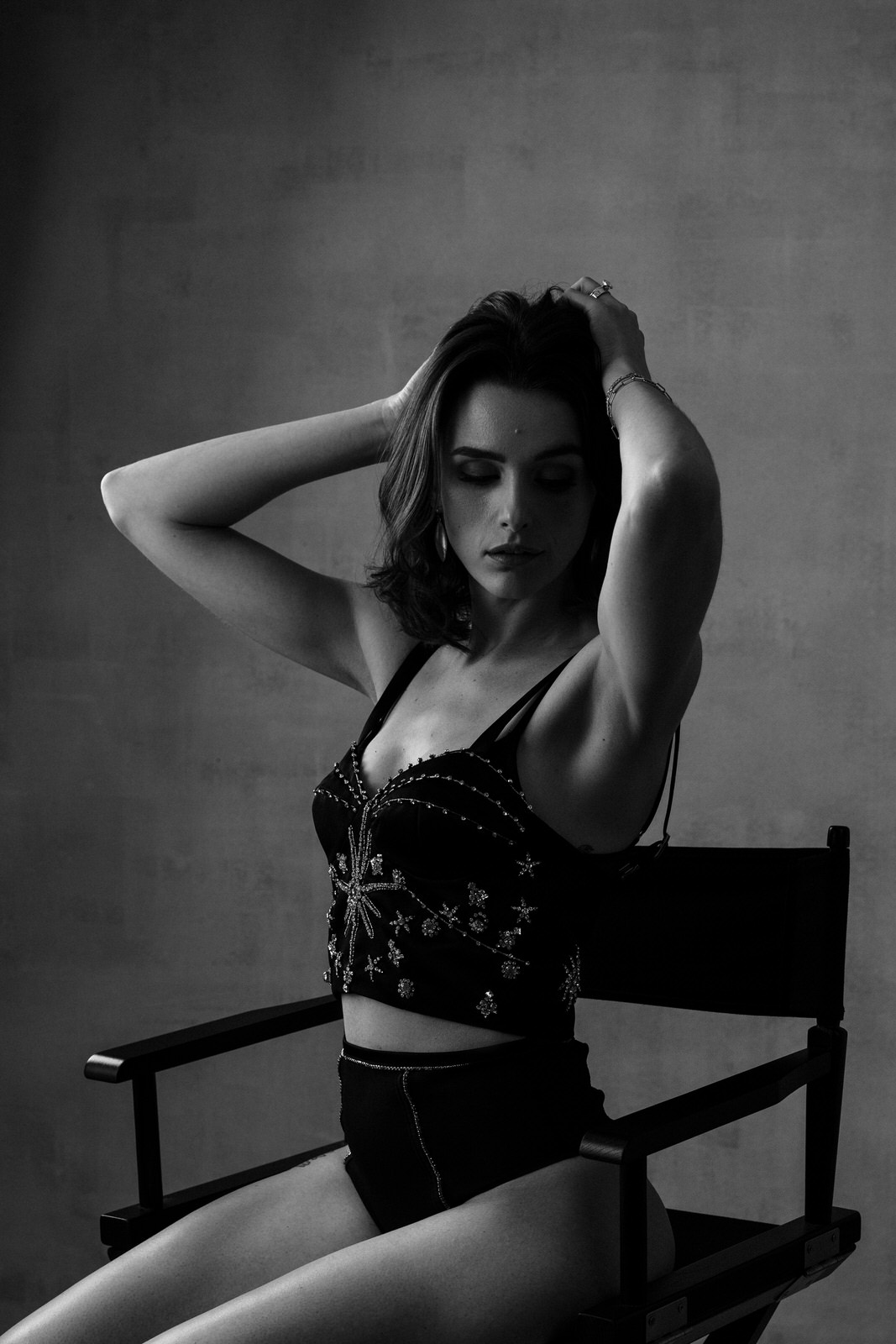 Vancouver Boudoir Photoshoot featuring a brunette woman sat on a director chair against a canvas backdrop, wearing Fleur du Mel lingerie looking away from the camera. The vibe is hollywood glam with a film vibe.