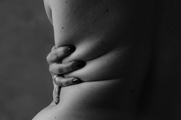 Black and white fine art portrait of nude woman's back with her hand on her waist