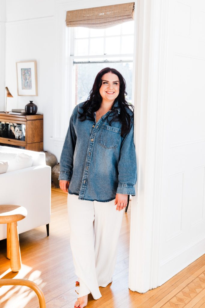 Portrait of a woman with brunette her hair in a trendy minimalist apartment setting wearing a denim top and white wide legged pants by Vancouver Portrait photographer Michele Mateus