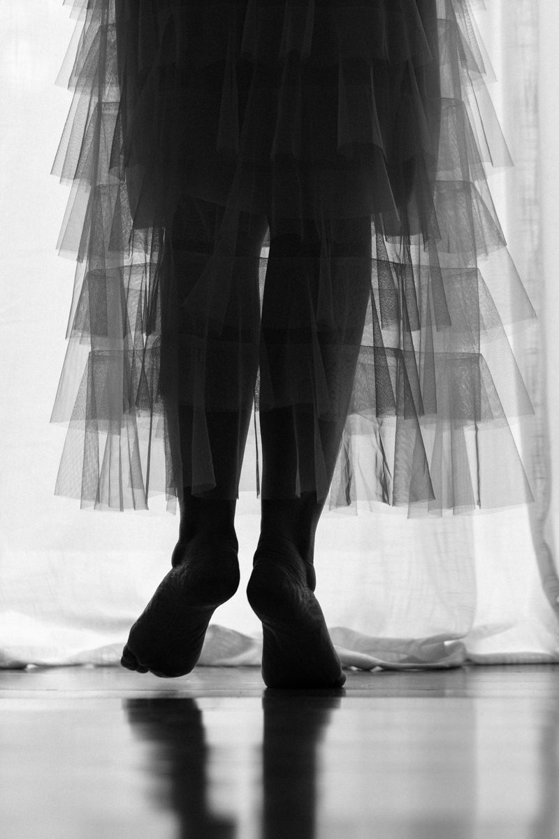 Woman's legs in black and white minimalist boudoir portrait with soft aesthetic wearing a tulle skirt.